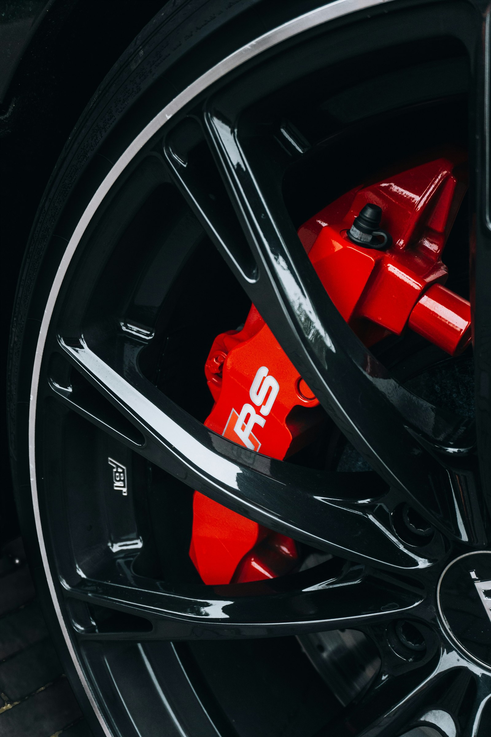 Red brake caliper behind a black alloy wheel